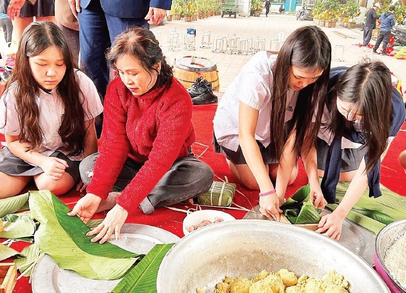 Students experience wrapping banh chung with members of the Intergenerational Self-Help Club in Khuong Dinh Ward (Ha Noi City).